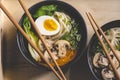 Flat-lay of Japanese rice noodleÃÂ  soup with mushrooms, aggs, Bok Choy, greens in black bowls